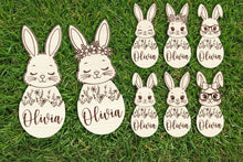 Load image into Gallery viewer, Set of bunny face cutouts with floral designs and the name on a wooden background.